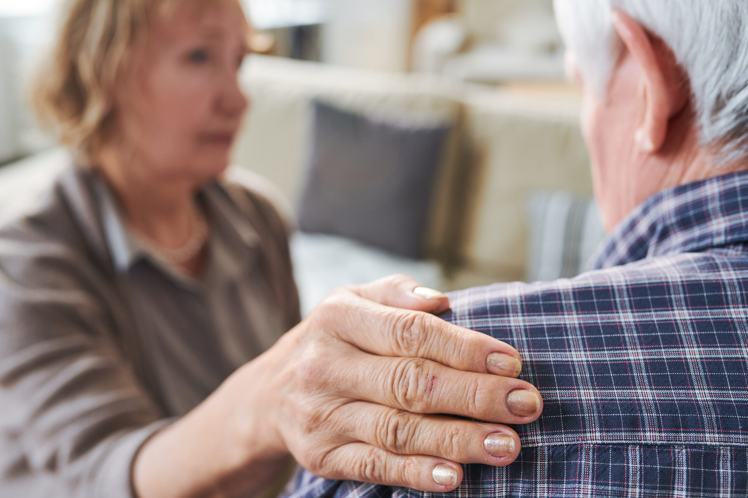 Hand of aged supportive wife on shoulder of her sick or stressed husband during support, sympathy or caregiving